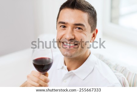 profession, drinks, leisure, holidays and people concept - happy man drinking red wine from glass at home