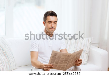 leisure, information, people and mass media concept - man reading newspaper at home