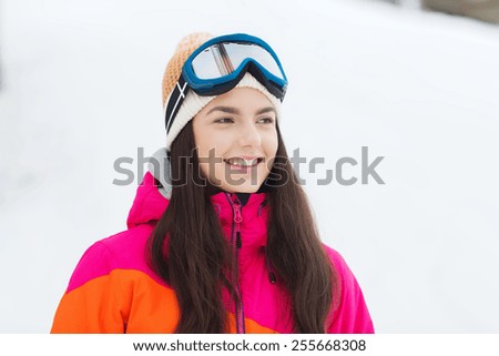 winter, leisure, sport and people concept - happy young woman in ski goggles outdoors