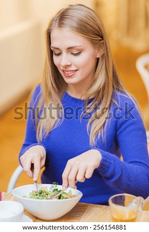 people, leisure, eating and food concept - happy young woman having dinner at restaurant, cafe or home