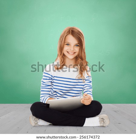education, school, technology, childhood and people concept - happy little student girl with tablet pc over green chalk board background