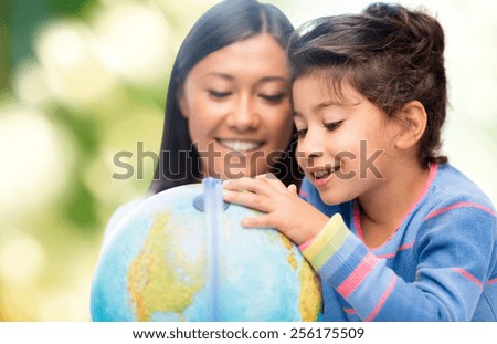 family, children, travel, geography and happy people concept - mother and daughter with globe over green background