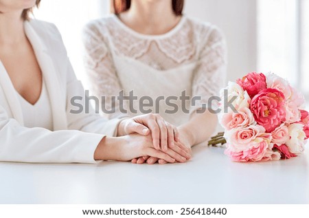 people, homosexuality, same-sex marriage and love concept - close up of happy married lesbian couple with flower bunch