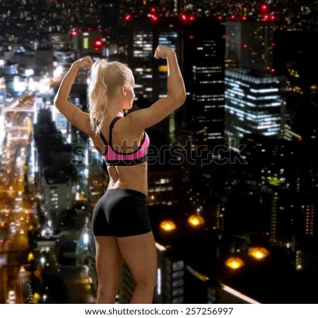 fitness, sport and diet concept - sporty woman from the back flexing her biceps