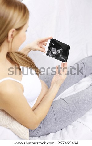 pregnancy, motherhood, people and medicine concept - happy pregnant woman looking at ultrasound image at home