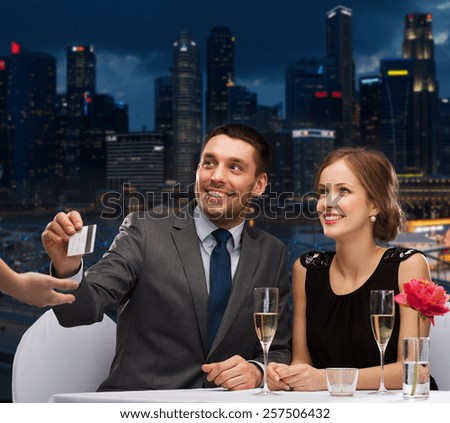 restaurant, people and holidays concept - smiling couple paying for dinner with credit card at restaurant over night city background
