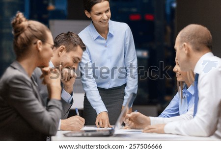 business, technology, people, deadline and team work concept - smiling female boss talking to business group at night office background