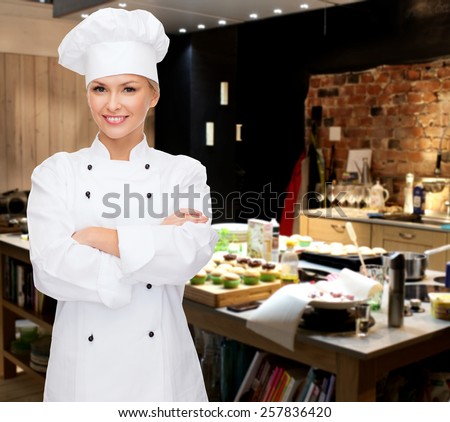 cooking, bakery, people and food concept - smiling female chef, cook or baker with crossed arms over restaurant kitchen background