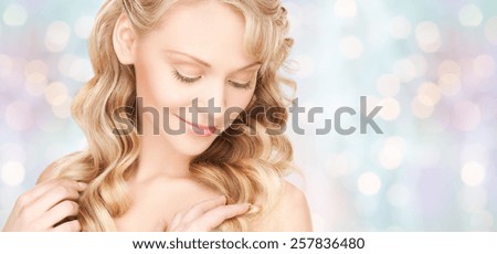 beauty, people, hair care and health concept - beautiful young woman face with long wavy hair over blue lights background
