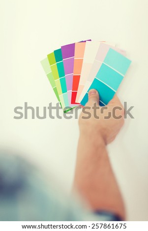 repair, building, technology and home concept - close up of male with color pallets choosing color