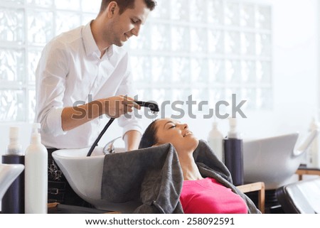 beauty and people concept - happy young woman with hairdresser washing head at hair salong