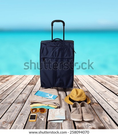 summer vacation, tourism and objects concept - travel bag, map, air ticket and clothes with personal stuff over wooden floor and sea background