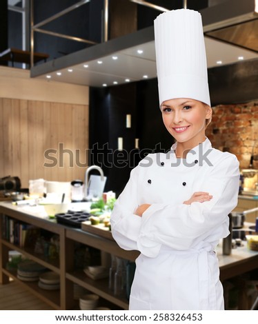 cooking, bakery, people and food concept - smiling female chef, cook or baker with crossed arms over restaurant kitchen background