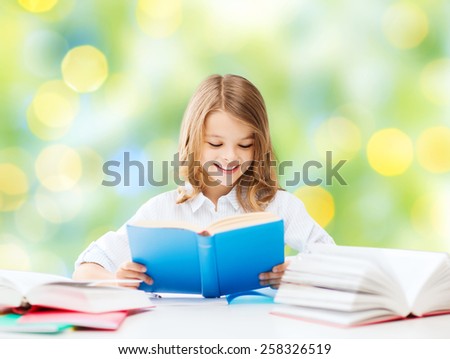 education, people, children and school concept - happy student girl reading book at school over green lights background