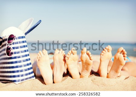 hats and summer concept - three women lying on the beach with straw hat, sunglasses and bag