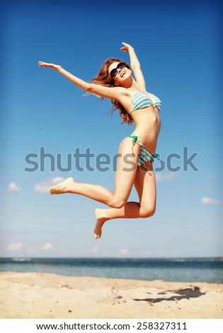 summer holidays and vacation concept - beautiful woman in bikini jumping on the beach