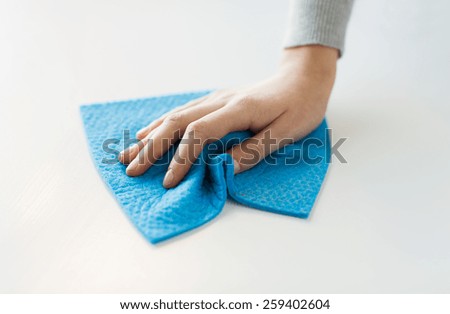 people, housework and housekeeping concept - close up of woman hand cleaning table surface with cloth at home