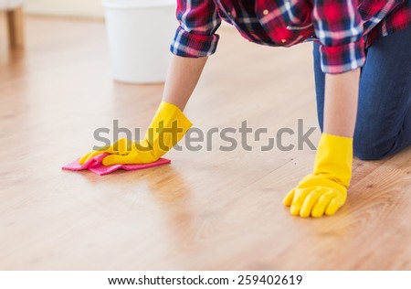 people, housework and housekeeping concept - close up of woman in rubber gloves with cloth cleaning floor at home