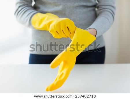 people, housework, safety and housekeeping concept - close up of woman hands wearing protective rubber gloves