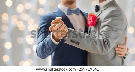 people, homosexuality, same-sex marriage and love concept - close up of happy male gay couple holding hands and dancing on wedding over holidays lights background