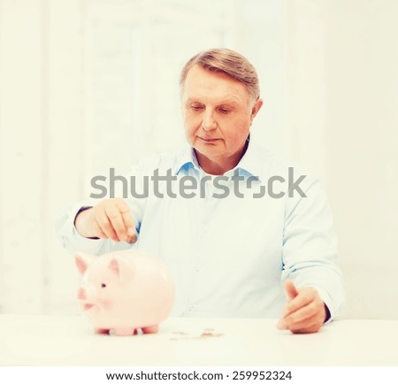 savings, oldness,business and banking concept - old man putting coin into big piggy bank
