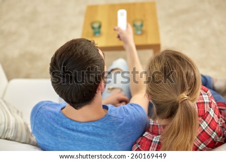 family, relations and leisure concept - close up of couple with remote control watching tv together at home