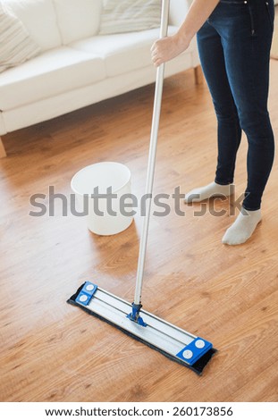 people, housework and housekeeping concept - close up of woman legs with mop cleaning floor at home