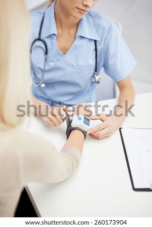 healthcare, cardiology, people and medicine concept - close up of female doctor with wrist tonometer measuring blood pressure or pulse rate to patient