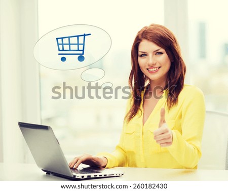 leisure, people, online shopping, gesture and technology concept - smiling young woman with laptop computer and trolley icon showing thumbs up at home