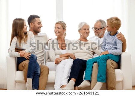 family, happiness, generation and people concept - happy family sitting on couch at home