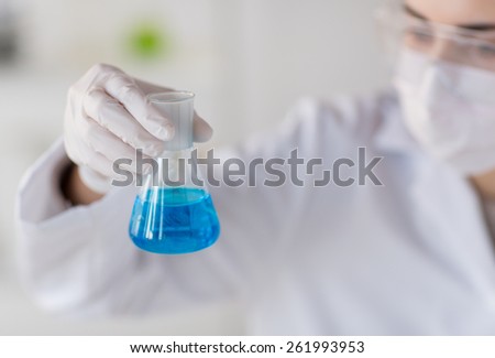 science, chemistry, biology, medicine and people concept - close up of young female scientist with flask making test or research in clinical laboratory