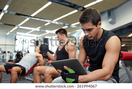 sport, bodybuilding, lifestyle, technology and people concept - group of men with tablet pc computer flexing muscles in gym