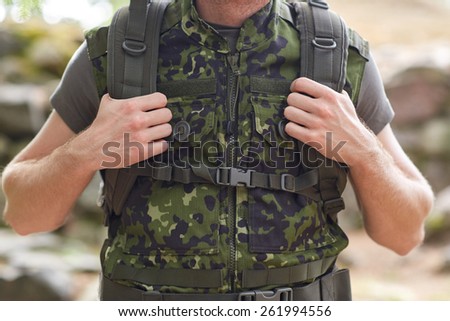war, hiking, army, camouflage equipment and people concept - close up of young soldier or ranger with backpack in forest