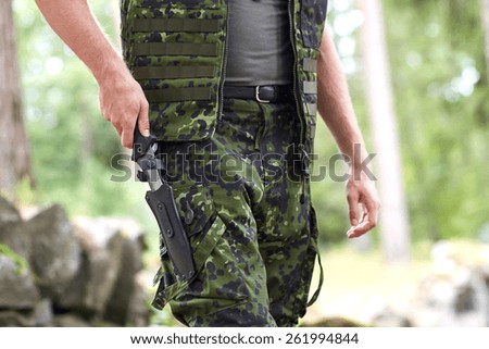 war, army, cold steel arms and people concept - close up of young soldier, ranger or hunter hands taking out knife in forest