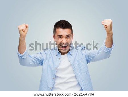 happiness, gesture, emotions, joy and people concept - happy laughing man with raised hands over gray background