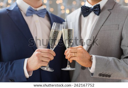 people, celebration, homosexuality, same-sex marriage and love concept - close up of happy married male gay couple drinking sparkling wine on wedding over holidays lights background