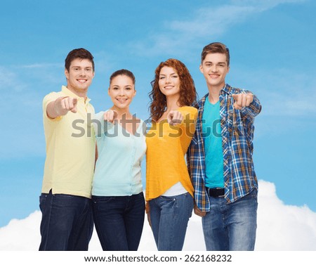 friendship, dream, future and people concept - group of smiling teenagers pointing fingers on you over blue sky with white cloud background