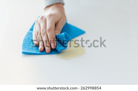 people, housework and housekeeping concept - close up of woman hand cleaning spot from table surface with cloth at home