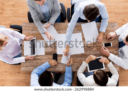 business, people and team work concept - close up of creative team with papers and gadgets meeting in office