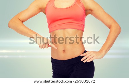 fitness, exercise and diet concept - close up of woman pointing finger at her six pack