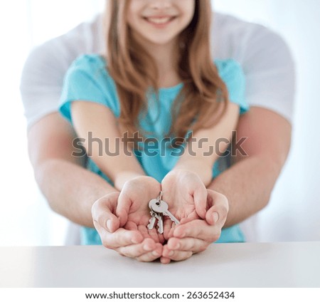 people, charity, family, real estate and home concept - close up of man and girl holding house keys in cupped hands