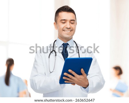 healthcare, profession, people and medicine concept - smiling male doctor in white coat with tablet pc over group of medics at hospital background