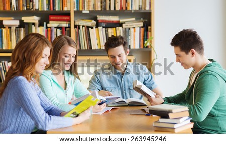 people, knowledge, education and school concept - group of happy students reading books and preparing to exam in library