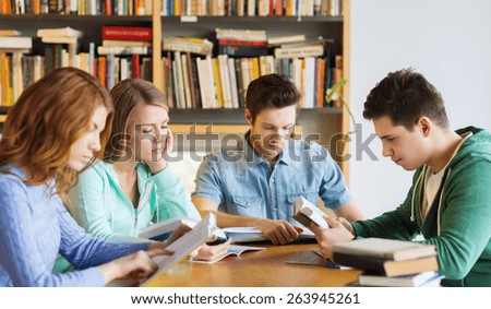 people, knowledge, education and school concept - group of students reading books and preparing to exam in library