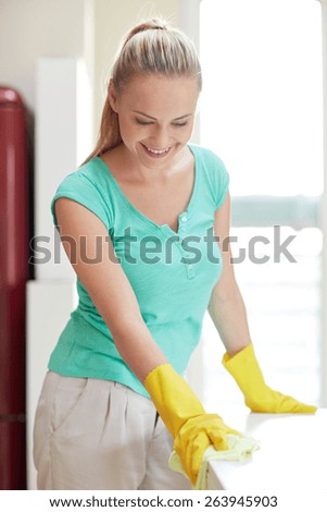 people, housework and housekeeping concept - happy woman cleaning table at home kitchen