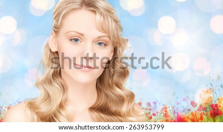 beauty, people, hair care and health concept - beautiful young woman face with long wavy hair over blue lights background