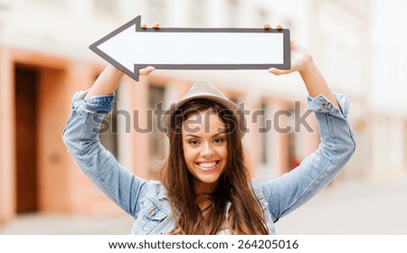 holidays and tourism concept - beautiful girl showing direction with arrow in the city