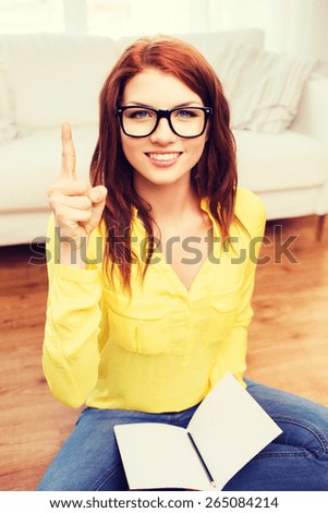 home, education, gesture and people concept - smiling teenage girl sitting on the floor with workbook at home