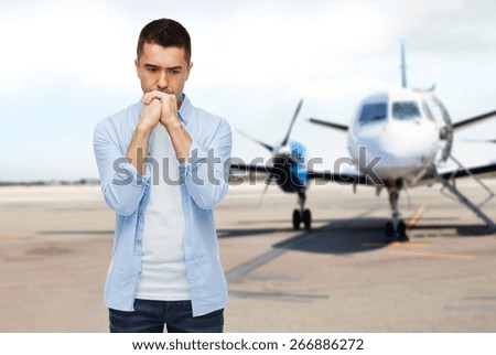phobia, fear, sorrow and people concept - unhappy man thinking over airplane on runway background