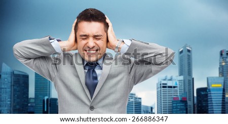 business, people, crisis and emotional pressure concept - businessman in suit covering his ears by hands over city background